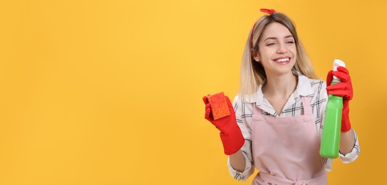 Young housewife with detergent and sponge on yellow background. Space for text