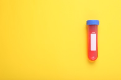 Photo of Test tube with liquid on yellow background, top view and space for text. Kids chemical experiment toy