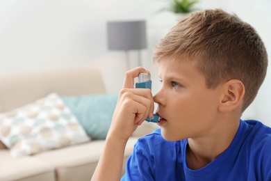 Photo of Little boy using asthma inhaler on blurred background