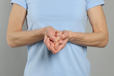 Woman cracking her knuckles on light grey background, closeup. Bad habit
