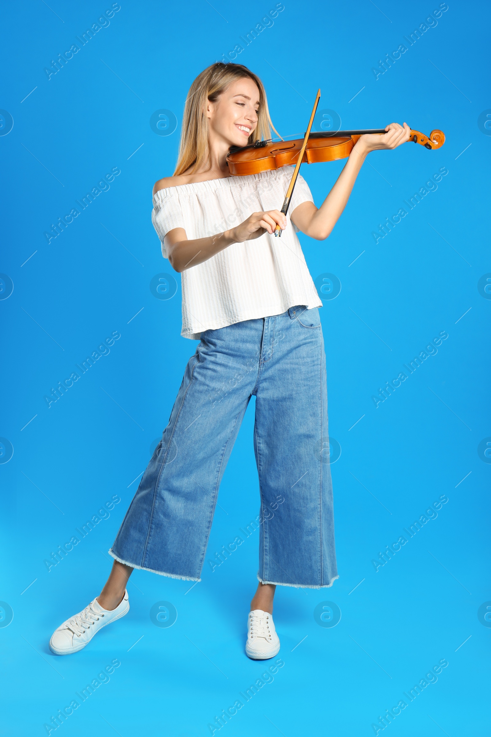 Photo of Beautiful woman playing violin on blue background