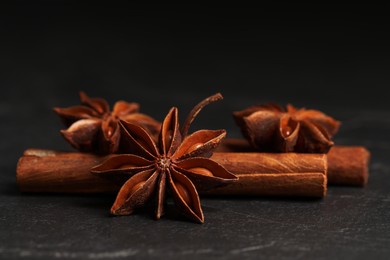 Photo of Aromatic anise stars and cinnamon sticks on black table