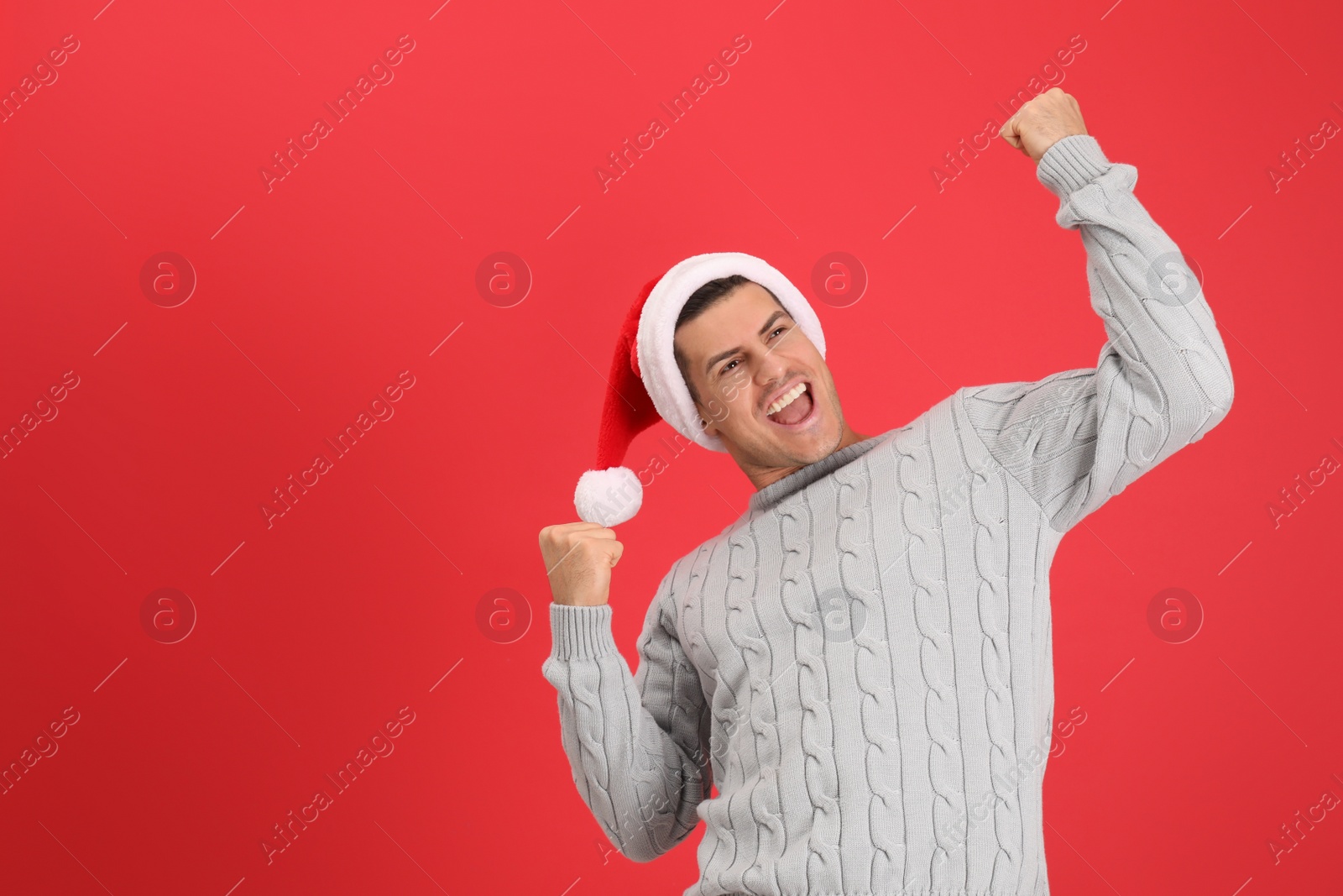Photo of Excited man wearing Santa hat on red background, space for text