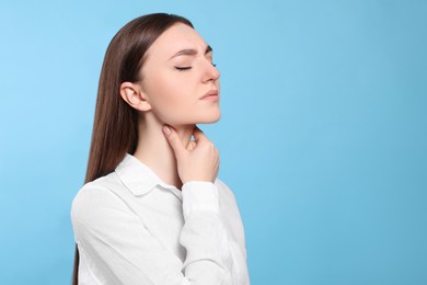 Photo of Young woman with sore throat on light blue background. Space for text
