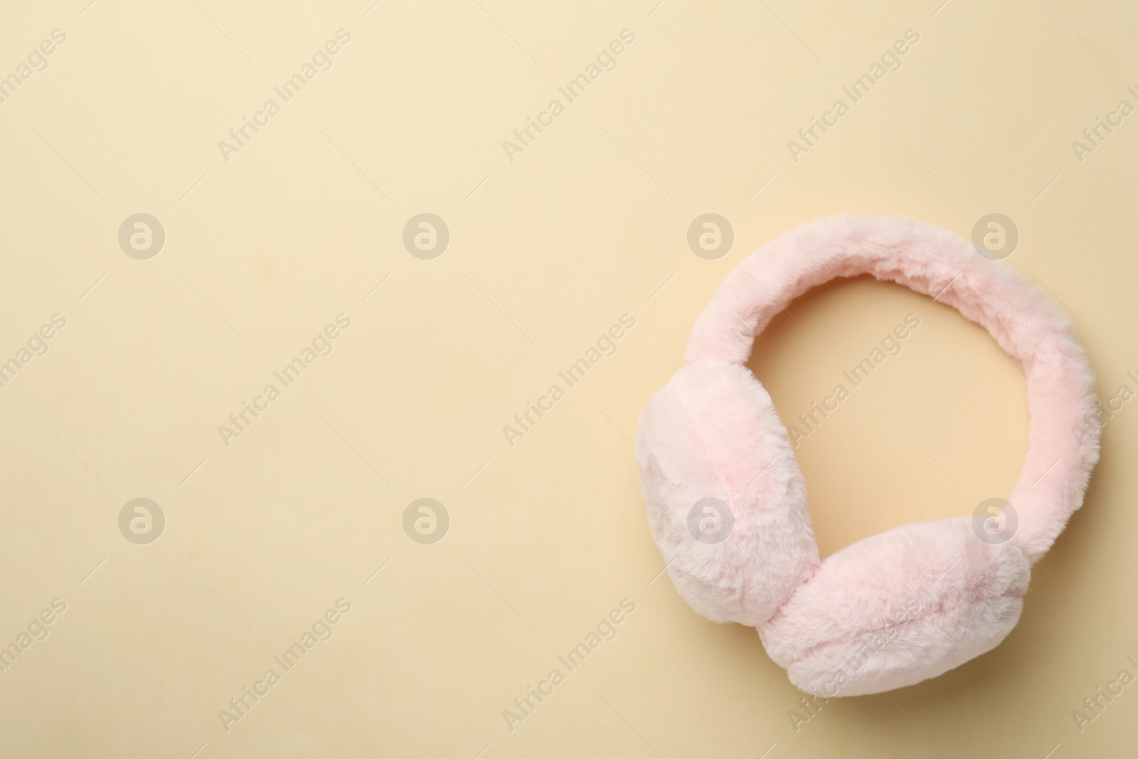 Photo of Stylish warm earmuffs on beige background, top view. Space for text