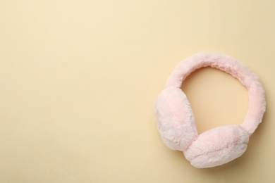 Photo of Stylish warm earmuffs on beige background, top view. Space for text