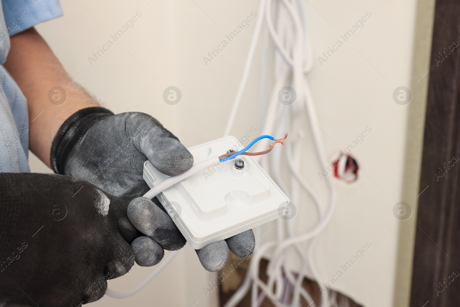 Photo of Electrician installing remote meter indoors, closeup. Installation of electrical wiring