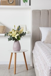 Photo of Bouquet of beautiful flowers on white table in bedroom
