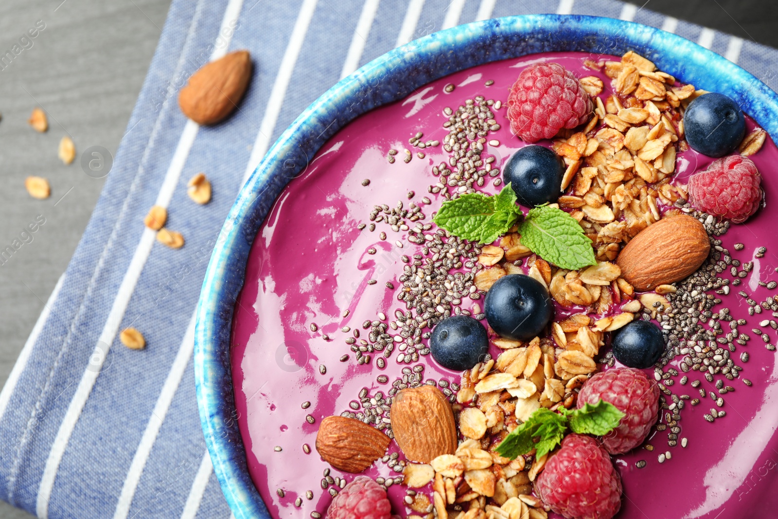Photo of Delicious acai smoothie with granola and berries in dessert bowl on table