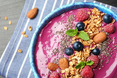 Delicious acai smoothie with granola and berries in dessert bowl on table