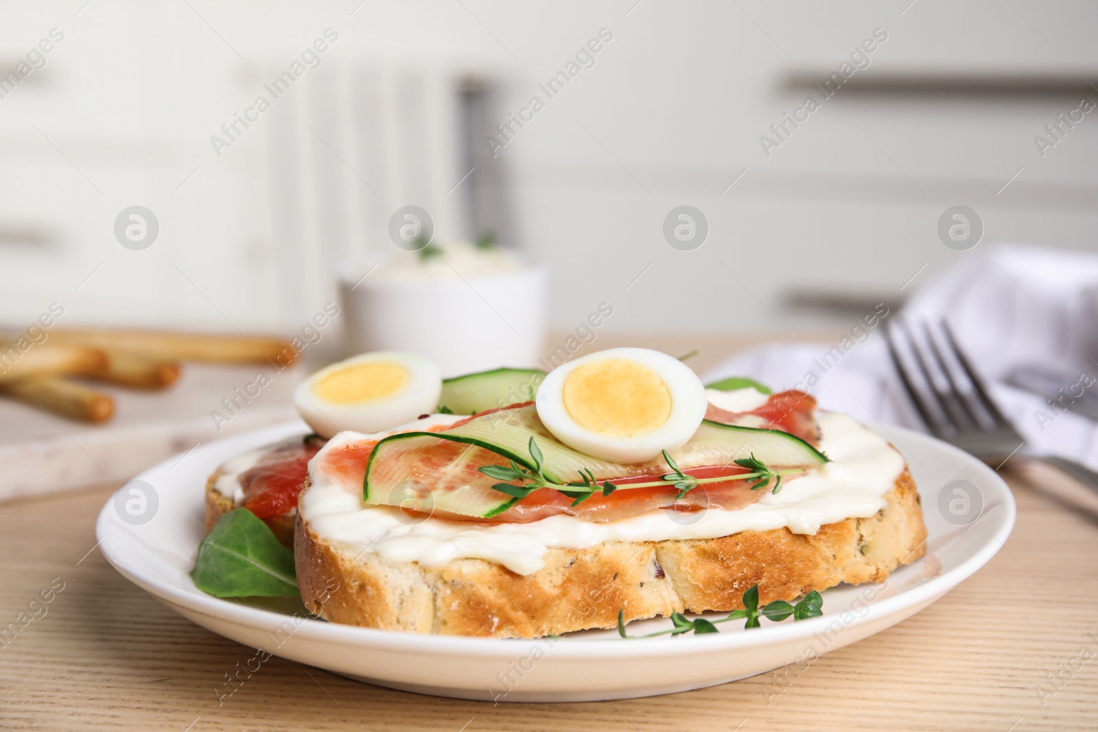 Photo of Plate of delicious bruschettas with salmon on wooden table in kitchen