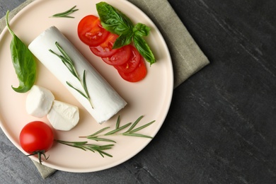 Photo of Delicious fresh goat cheese with tomatoes, basil and rosemary on grey table, flat lay