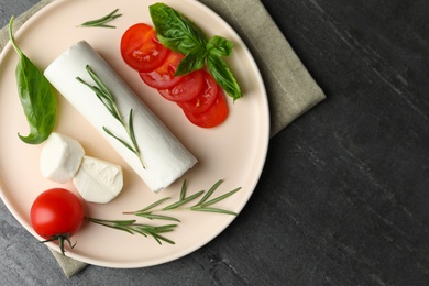 Delicious fresh goat cheese with tomatoes, basil and rosemary on grey table, flat lay