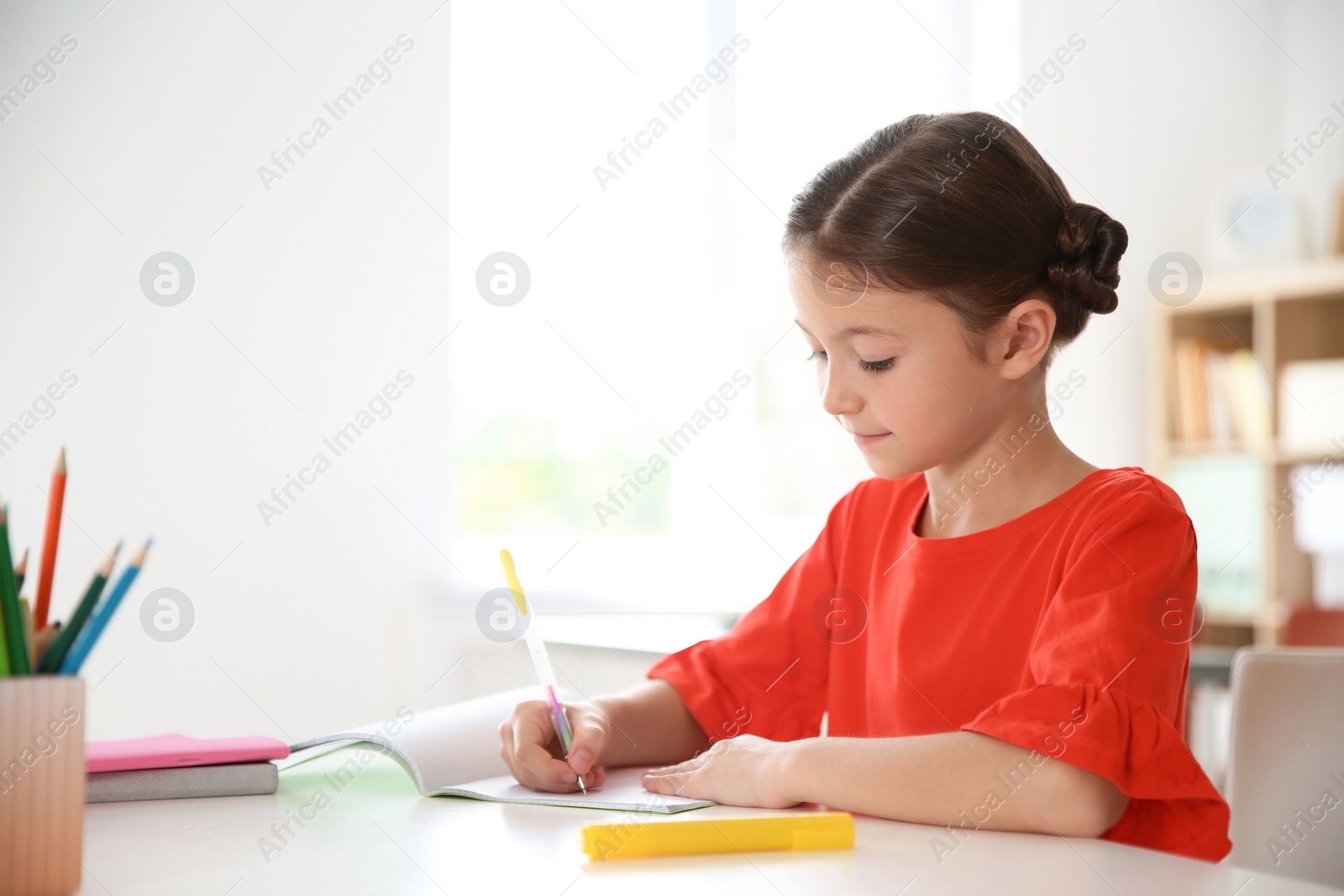 Photo of Cute little child doing assignment at desk in classroom. Elementary school