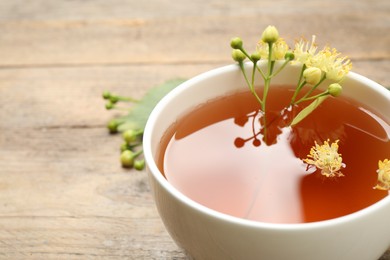 Photo of Cup of tea with linden blossom on table, closeup. Space for text