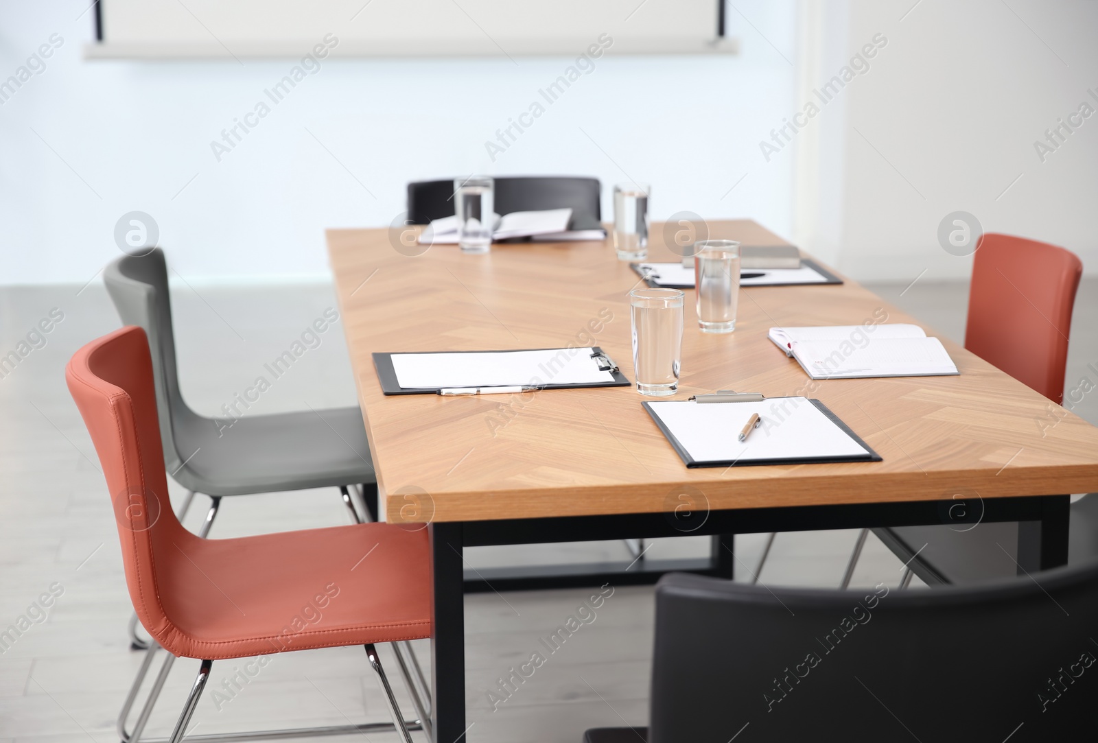 Photo of Clipboards and glasses of water on wooden table in modern office