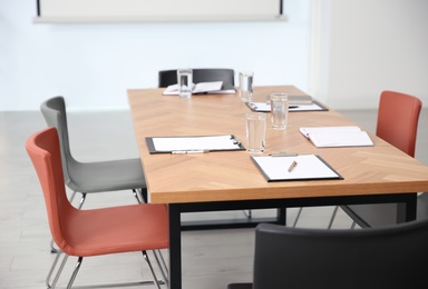 Clipboards and glasses of water on wooden table in modern office