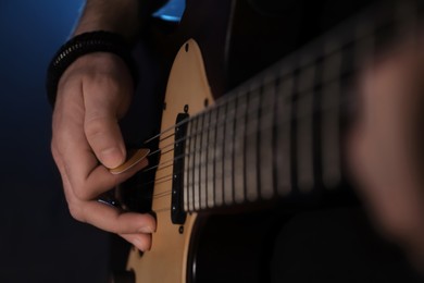 Photo of Man playing electric guitar on dark background, closeup. Rock music