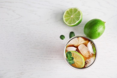 Flat lay composition with glass of coke and ice cubes on wooden background. Space for text