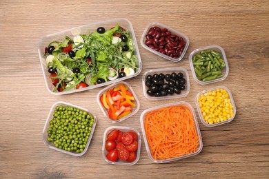 Set of plastic containers with fresh food on wooden  table, flat lay