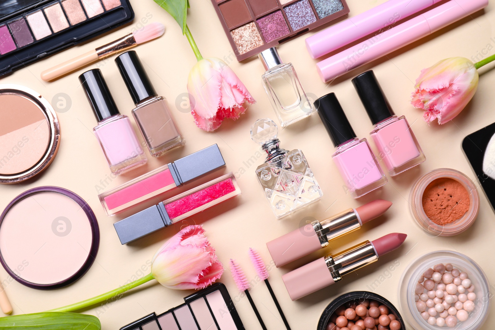 Photo of Flat lay composition with different makeup products and beautiful spring flowers on beige background