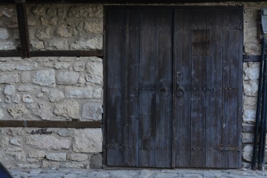 Entrance of building with old wooden doors in stone wall outdoors
