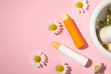 Flat lay composition with hygienic lipsticks on pink background