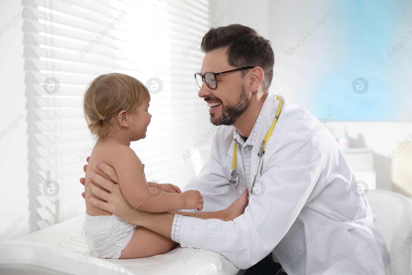 Photo of Pediatrician examining cute little baby in clinic