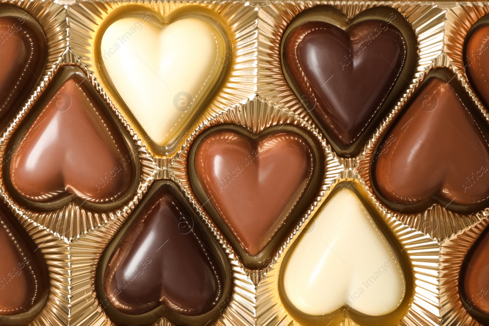 Photo of Beautiful heart shaped chocolate candies in box as background, top view