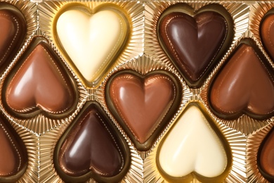 Beautiful heart shaped chocolate candies in box as background, top view