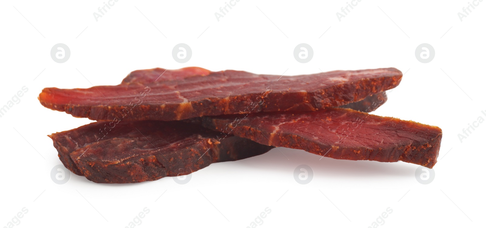 Photo of Pieces of delicious beef jerky on white background