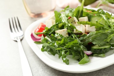 Photo of Delicious salad with feta cheese, arugula and vegetables on grey table, closeup