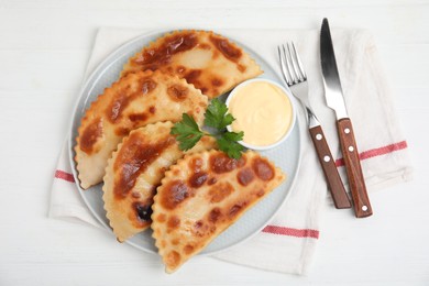 Photo of Delicious fried chebureki with sauce served on white table, top view