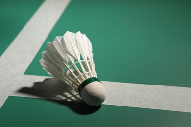 Photo of Feather badminton shuttlecock on court, space for text