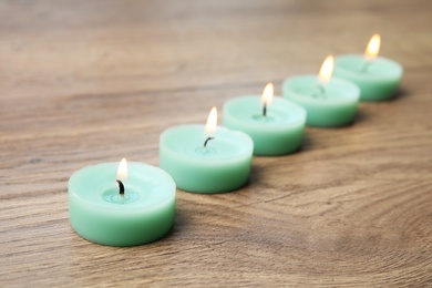 Photo of Burning turquoise decorative candles on wooden table