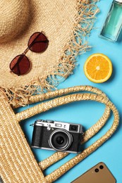 Photo of Flat lay composition with wicker bag and other beach accessories on light blue background
