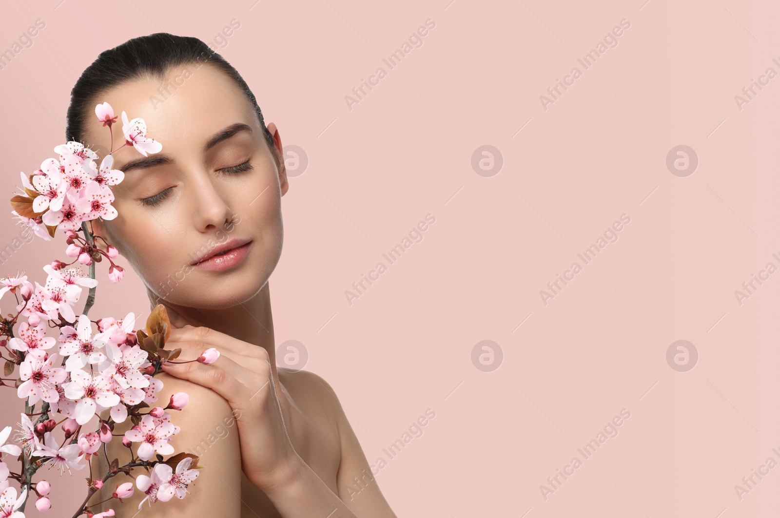 Image of Beautiful woman with smooth skin and flowers on beige pink background. Space for text