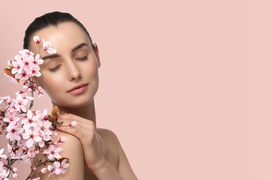 Image of Beautiful woman with smooth skin and flowers on beige pink background. Space for text