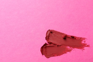 Photo of Smears of beautiful lipstick on pink background, top view. Space for text