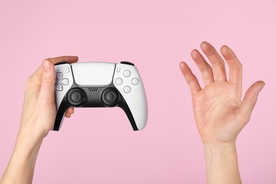 Woman with game controller on pink background, closeup