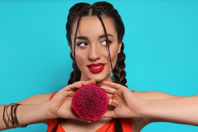 Photo of Young woman with fresh pitahaya on light blue background. Exotic fruit