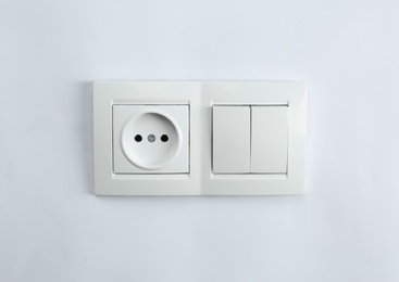 Photo of Light switch and power socket on white background. Electrician's equipment