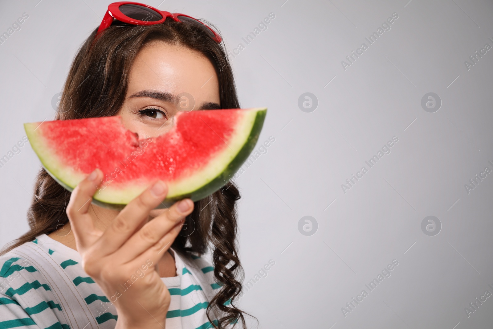 Photo of Beautiful young woman with watermelon on grey background. Space for text