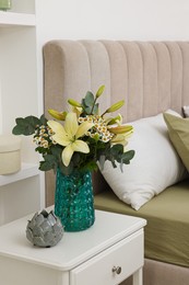 Photo of Bouquet of beautiful flowers and ceramic decor on nightstand in bedroom