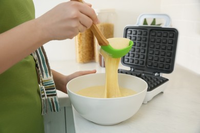 Photo of Woman preparing dough near Belgian waffle maker in kitchen, closeup