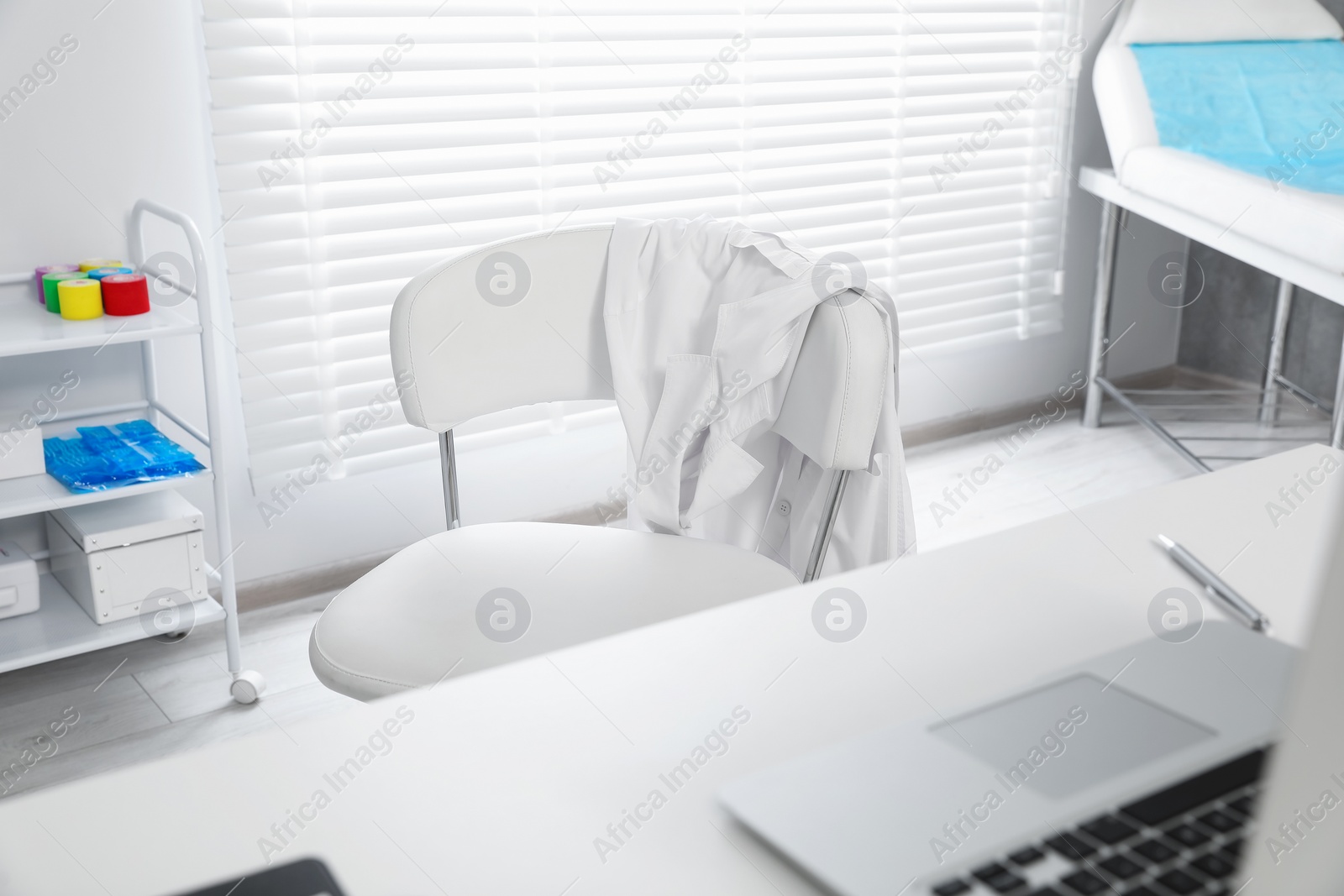 Photo of White doctor's gown hanging on chair in clinic