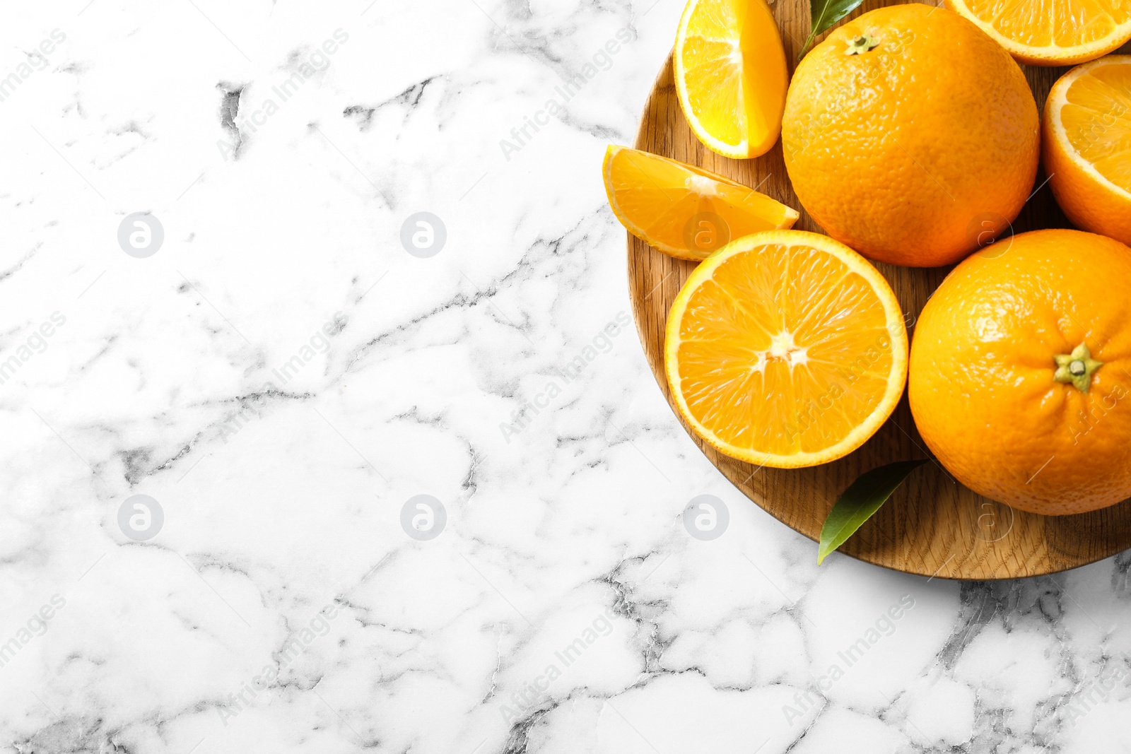 Photo of Plate with ripe oranges on marble background, top view. Space for text