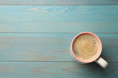 Cup of aromatic coffee on light blue wooden table, top view. Space for text