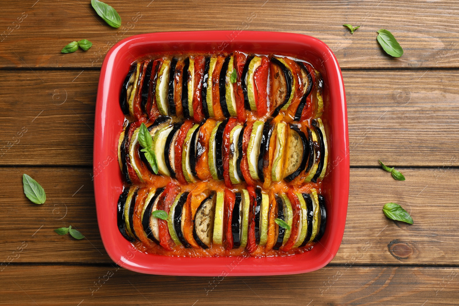 Photo of Delicious ratatouille in baking dish on wooden table, top view