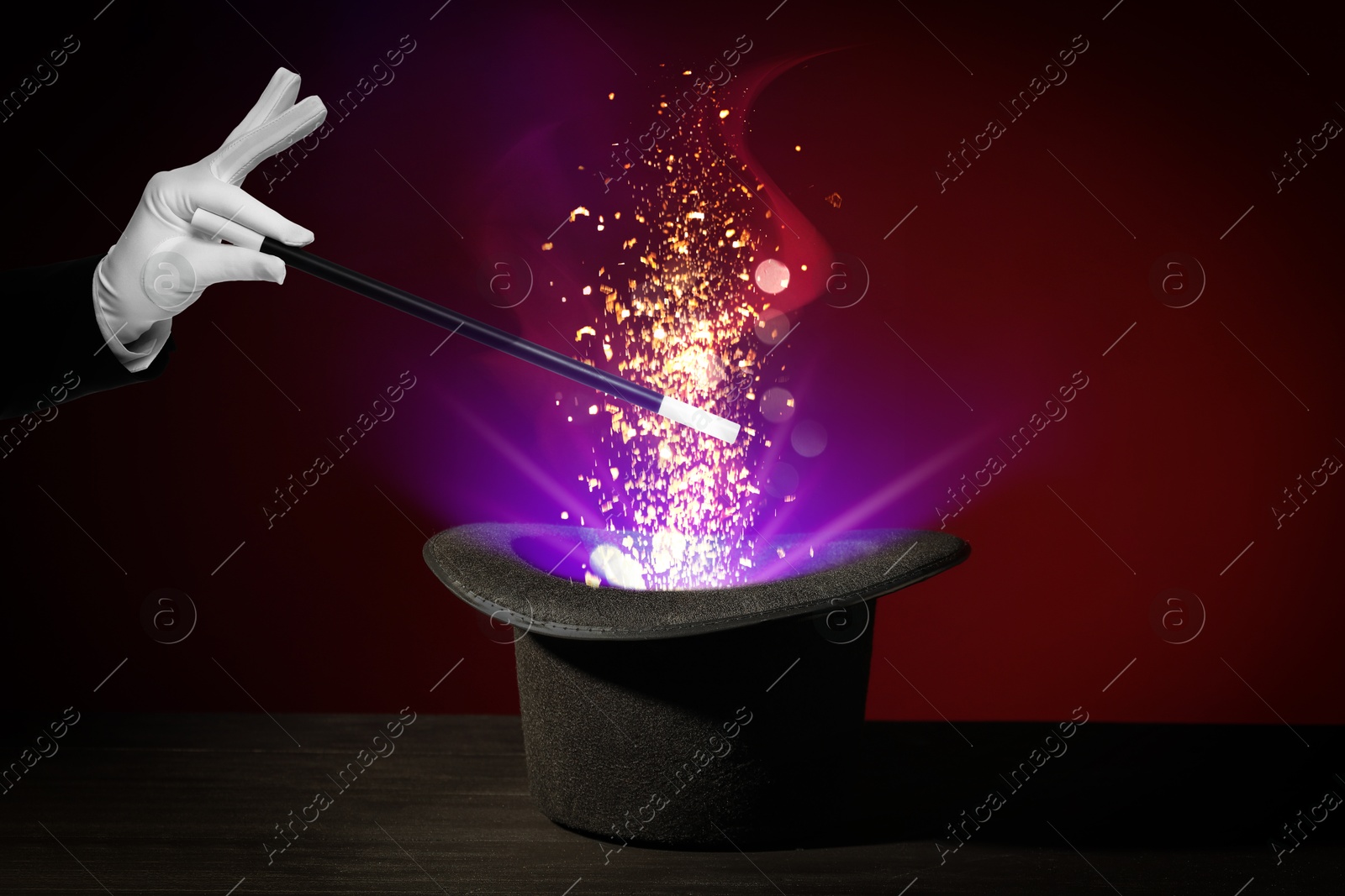 Image of Wizard conjuring magical light out of hat with wand on dark background, closeup